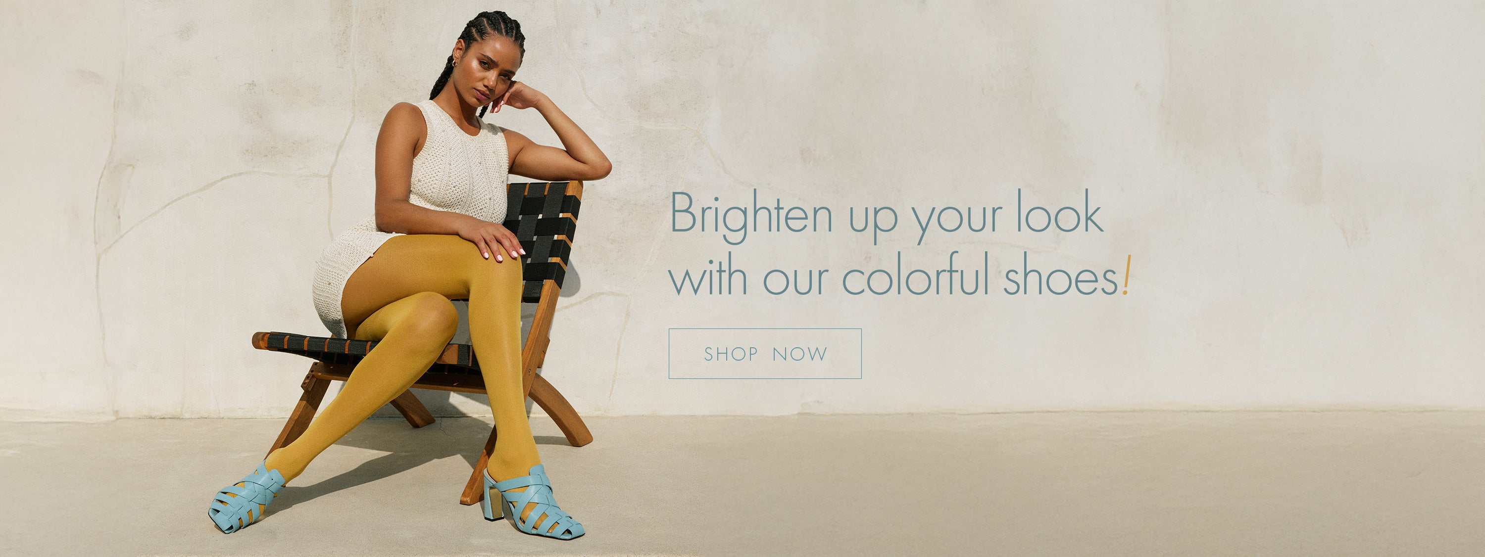 woman sitting on wood chair with yellow tights and a white knit dress with the copy Brighten up your look - shop now